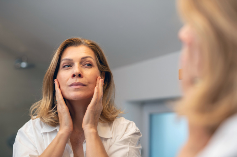 középkorú nő skincare rutint tart