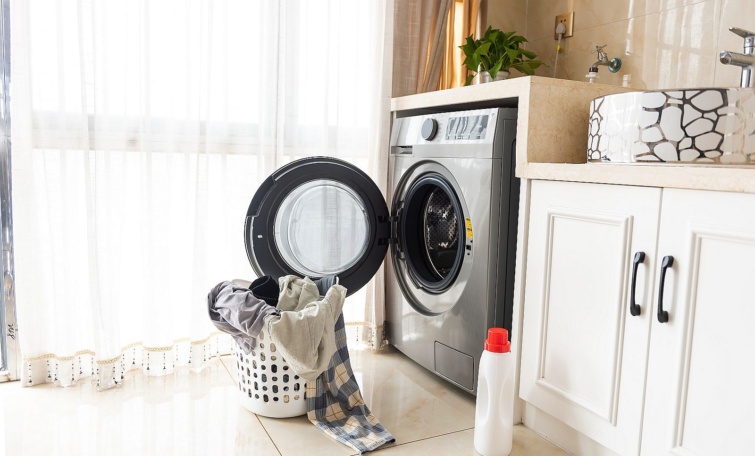 Asian man using washing machine at home Laundry day Startlap Vásárlás Szennyes egy kosárban egy nyitott ajtajú mosógép előtt.