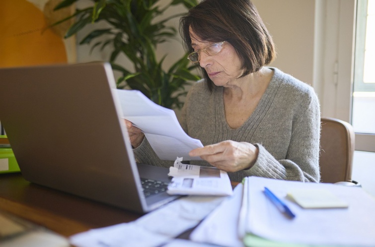 Senior woman reviewing tax documents at home with laptop Startlap Vásárlás Idős szemüveges nő egy levelet olvas gondterhelten a laptop előtt.